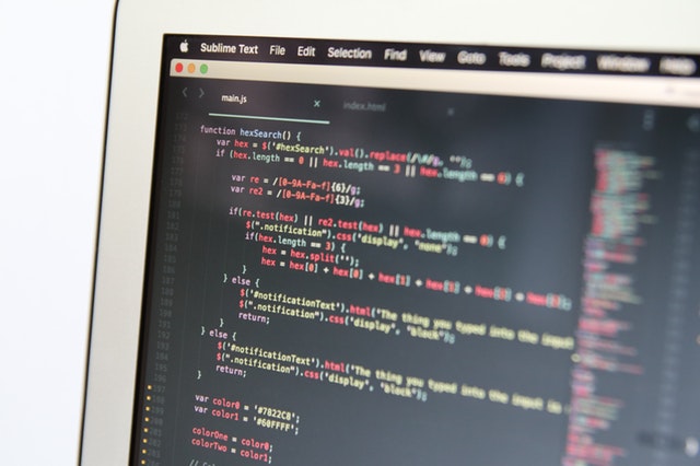 A close-up of a laptop screen shows a system of code in development.