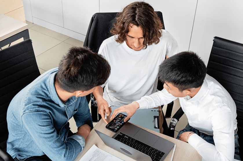 Men sit around a desk collaborating.