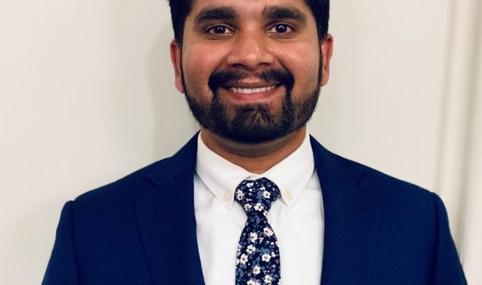 A portrait shows Umair Khakoo wearing a suit and smiling at the camera.