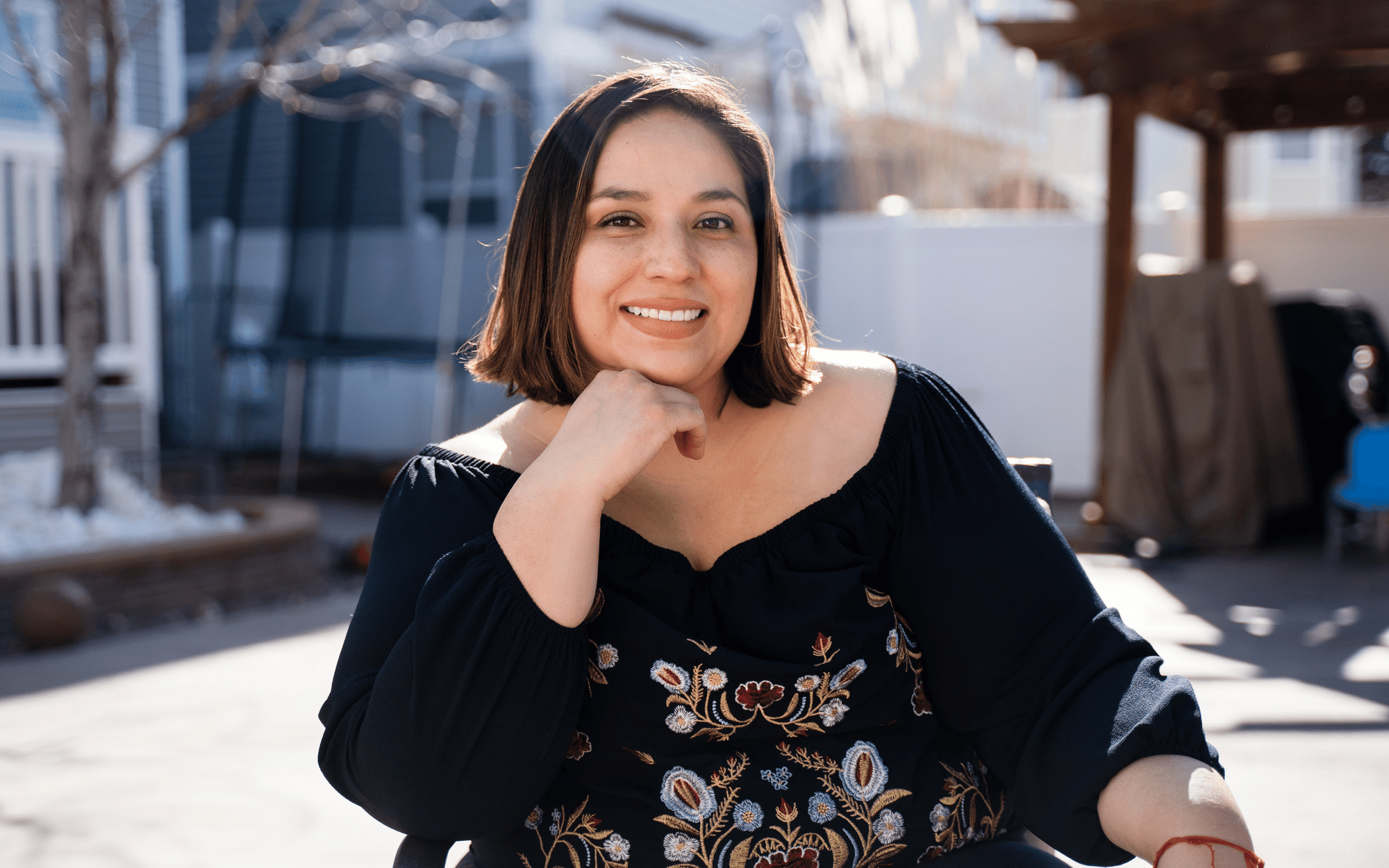 Erica Gonzalez is seated at an outdoor restaurant, giving a relaxed smile to the camera.