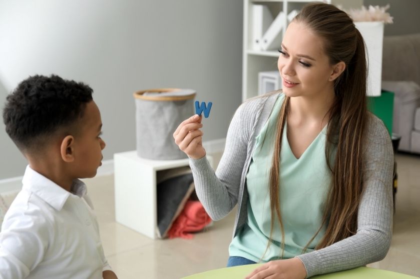 woman holding up the letter "W" to a child