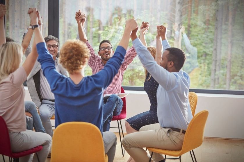 group in chairs with hands raised together