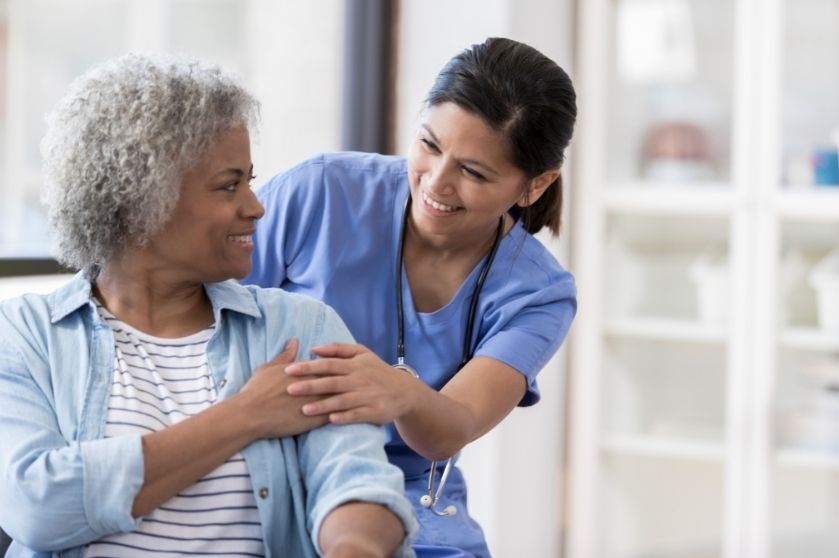 Female nurse smiling at patient while offering a soothing hand