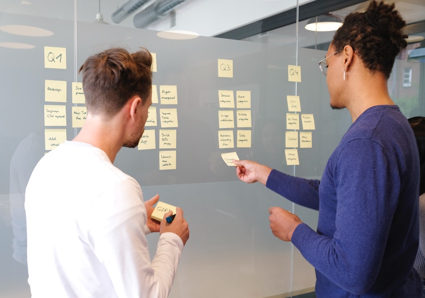 Two people work at a whiteboard.