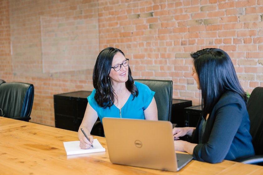 Two women sit in front of a laptop.